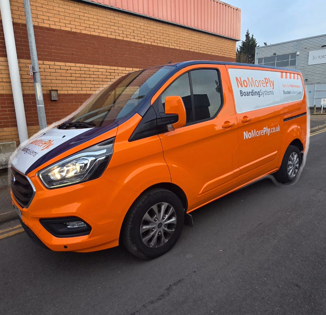 Orange and white van branded with NoMorePly Boarding Systems signage parked on a street near industrial buildings